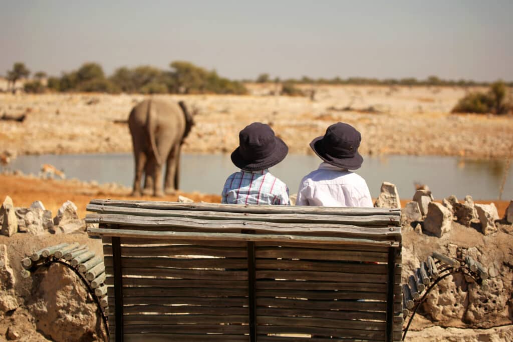 Children Watching Elephant At Okaukuejo Waterhole in Etosha Namibia