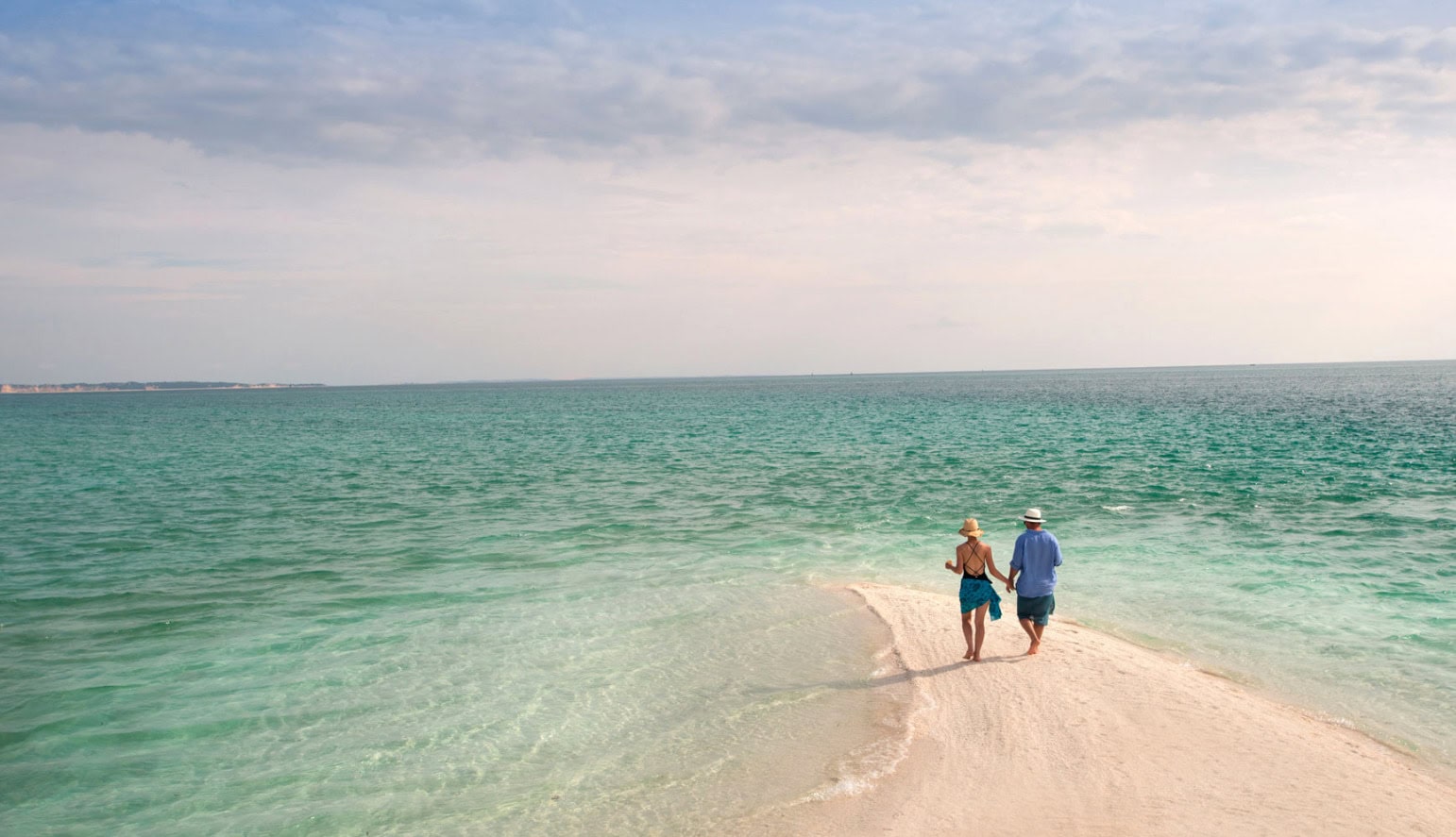 Couple holding hands while walking on the beach during the day