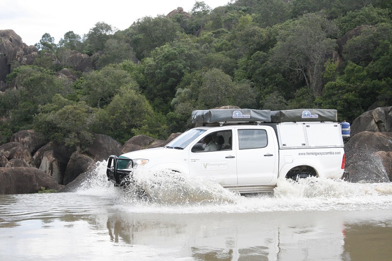 Driving through a river on a self-drive safari in Zambia.