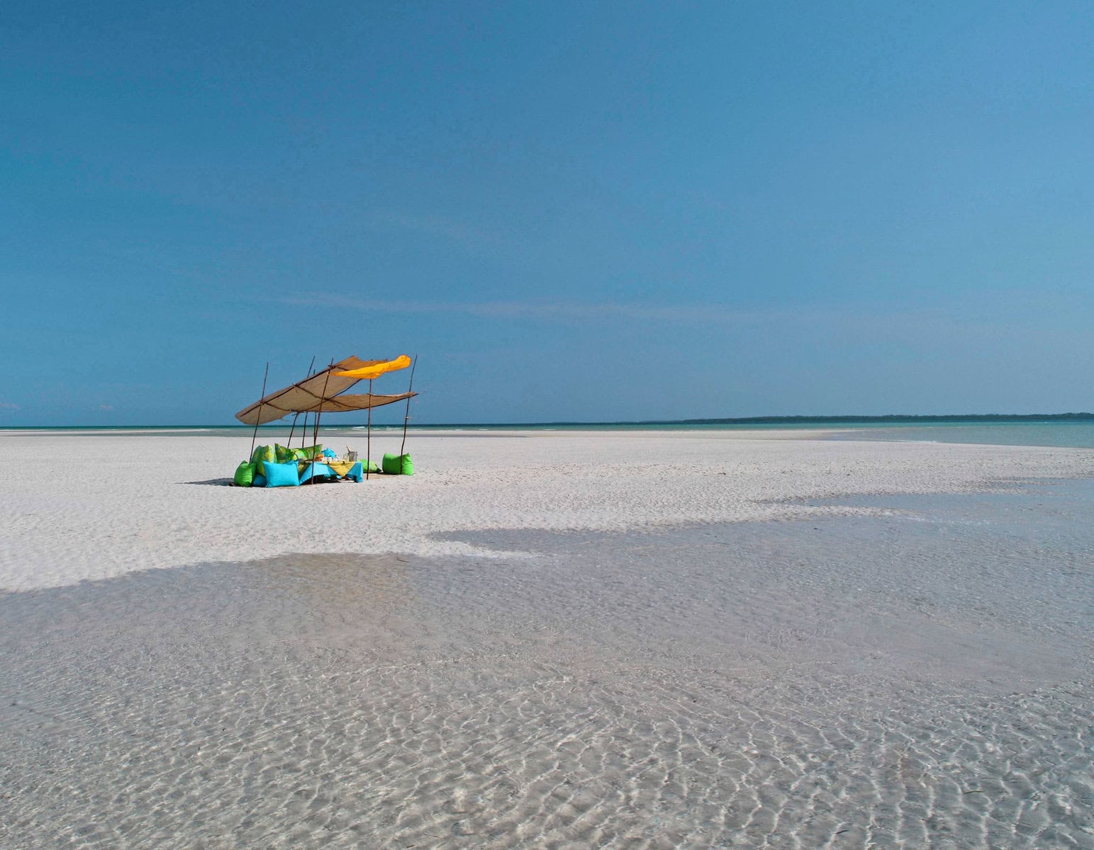 Seating on a sandbank at Funzi Keys. A beach bag is important to have on your Kenya safari packing list, especially if you're going to the beach.