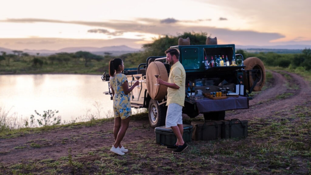 Couple having drinks next to a river while on safari