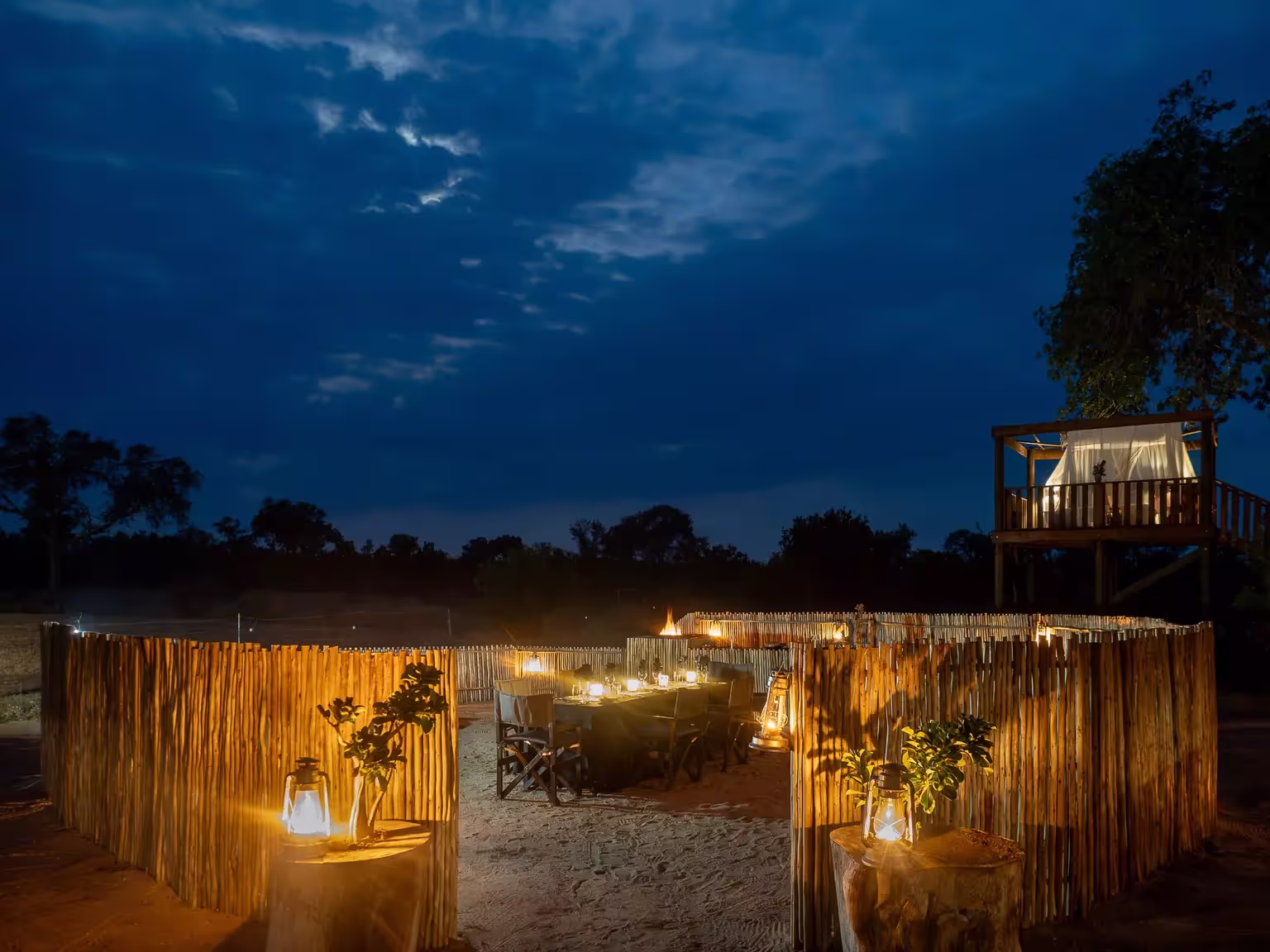 A view of the candle lit outdoor dining area under the night sky at Tintswalo Manor, South Africa.