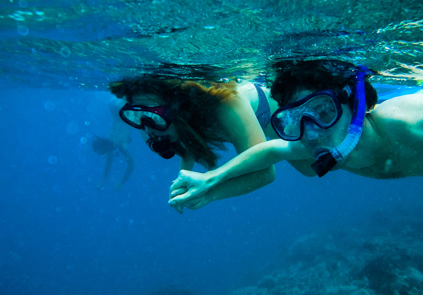 A couple holding hands underwater while snorkelling